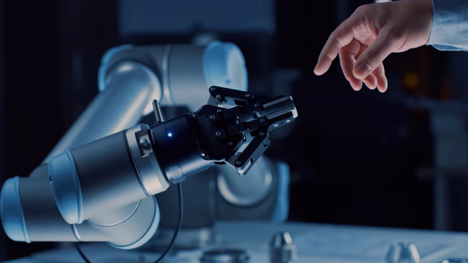 Menschliche Hand streckt sich einer Greifarmroboterhand in dunkler, technologischer Umgebung entgegen.